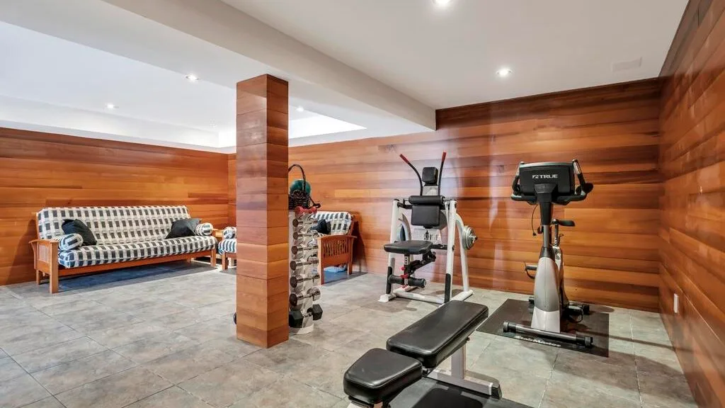 A compact gym with exercise bikes, weight equipment, and a bench.