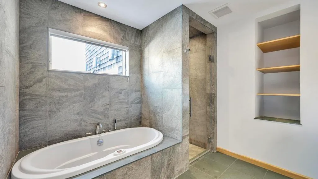 A modern bathroom with a built-in bathtub and an open shower area.