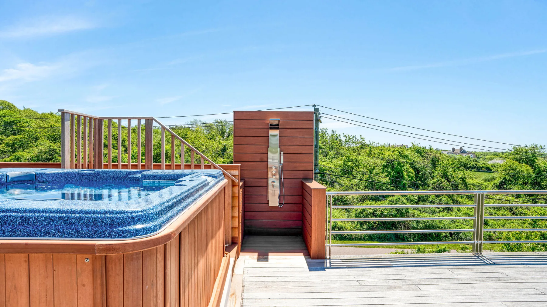 An outdoor deck features a raised hot tub beside a wooden privacy screen.