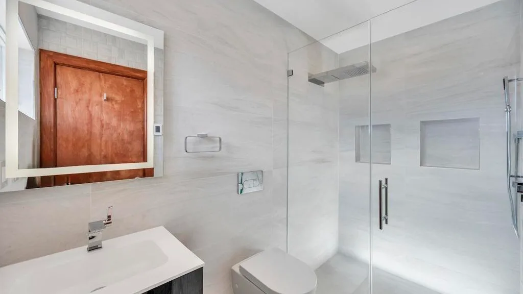 A bright bathroom with a sink and glass shower.