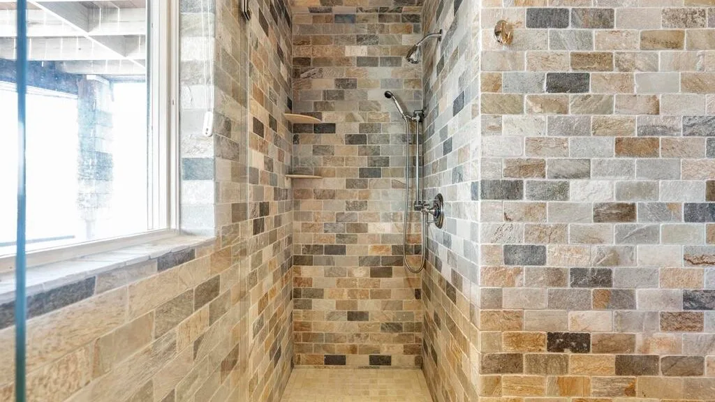 A tiled shower area with a wall-mounted showerhead beside a window.