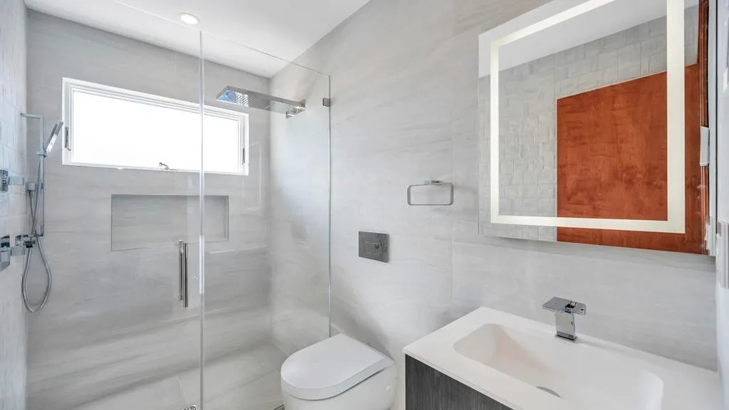 A bright tiled bathroom with a glass shower and a white sink.