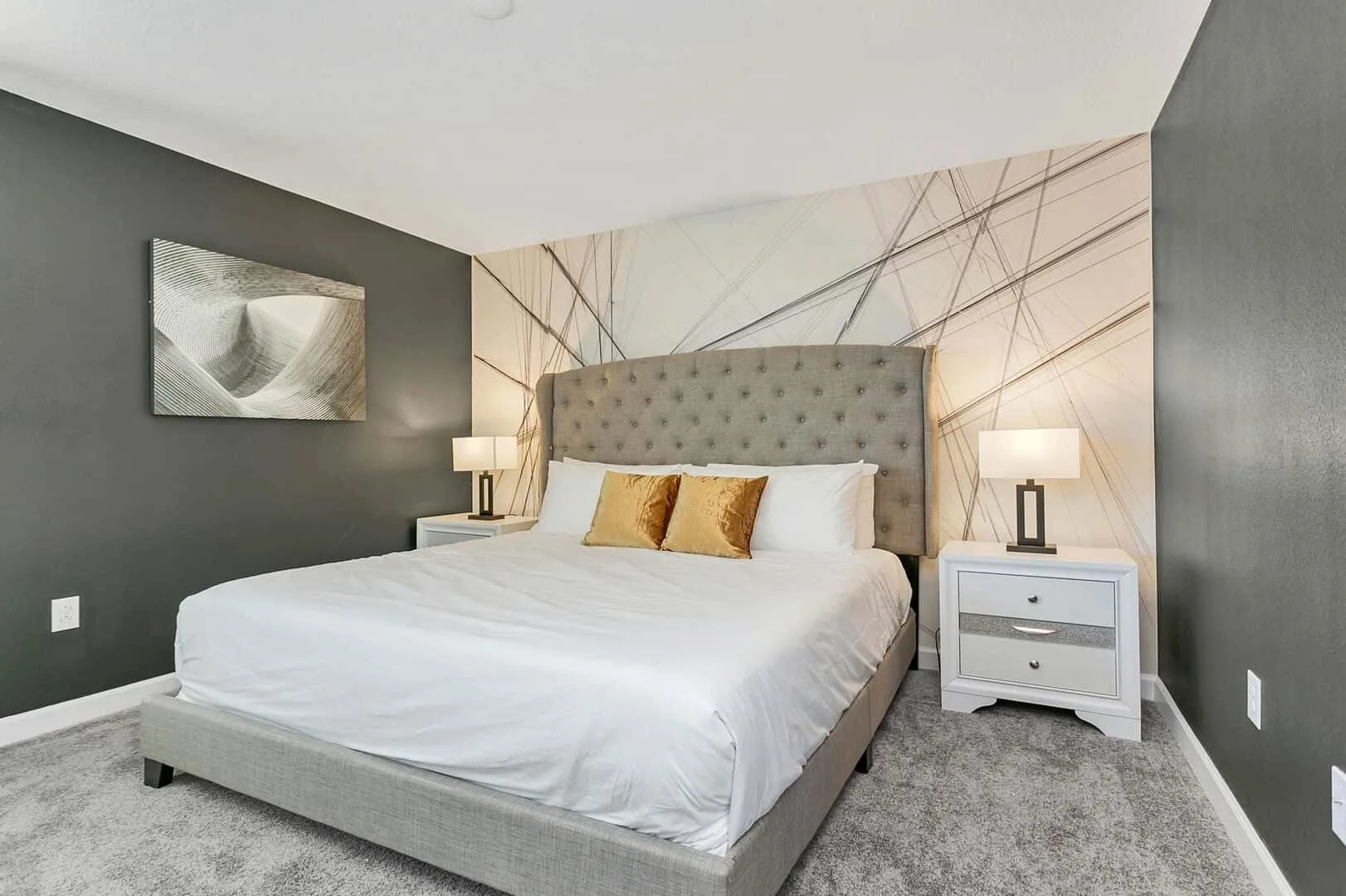 Un dormitorio con una cama grande, mesas de noche y arte geométrico en la pared.