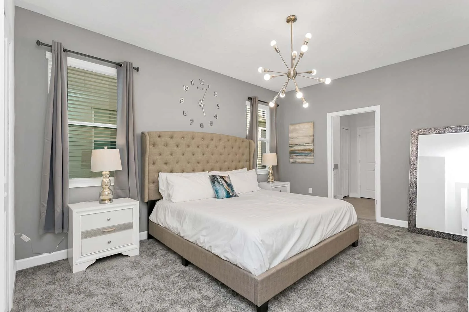Un dormitorio con una cama grande, mesitas de noche y alfombra gris.
