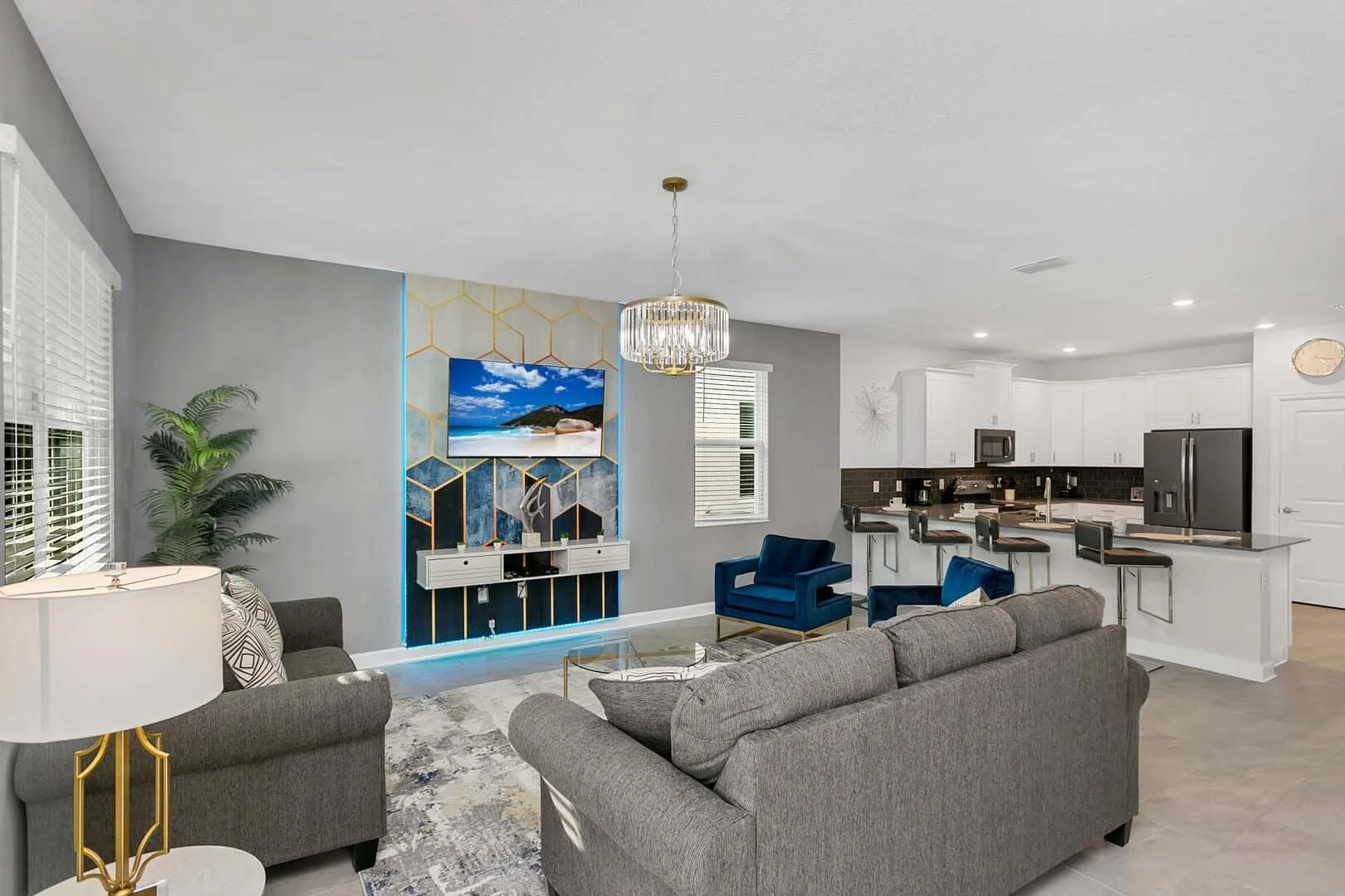 Una sala de estar se abre a una cocina, con un televisor sobre un mueble decorativo.