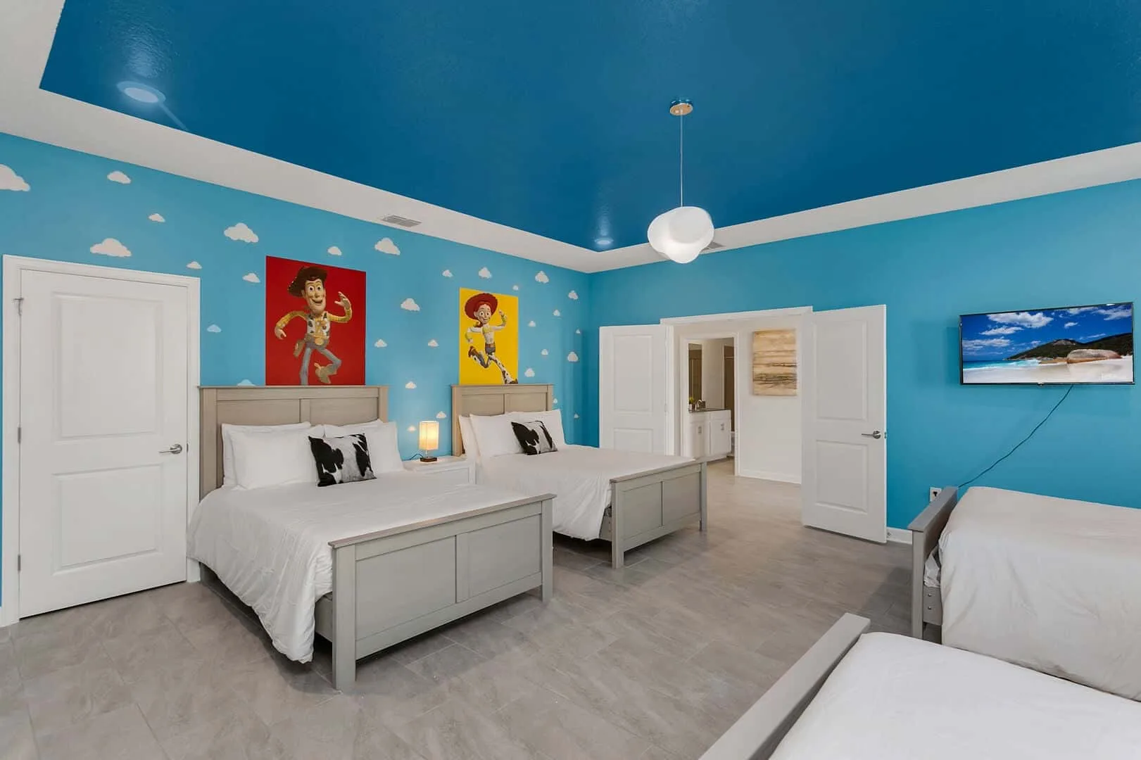 Un dormitorio colorido con varias camas, paredes azules y arte mural lúdico.
