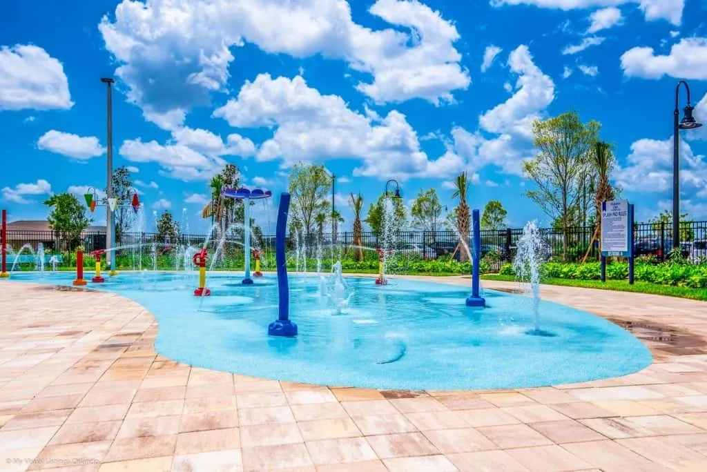 Una zona de juegos acuáticos al aire libre junto a un patio pavimentado.