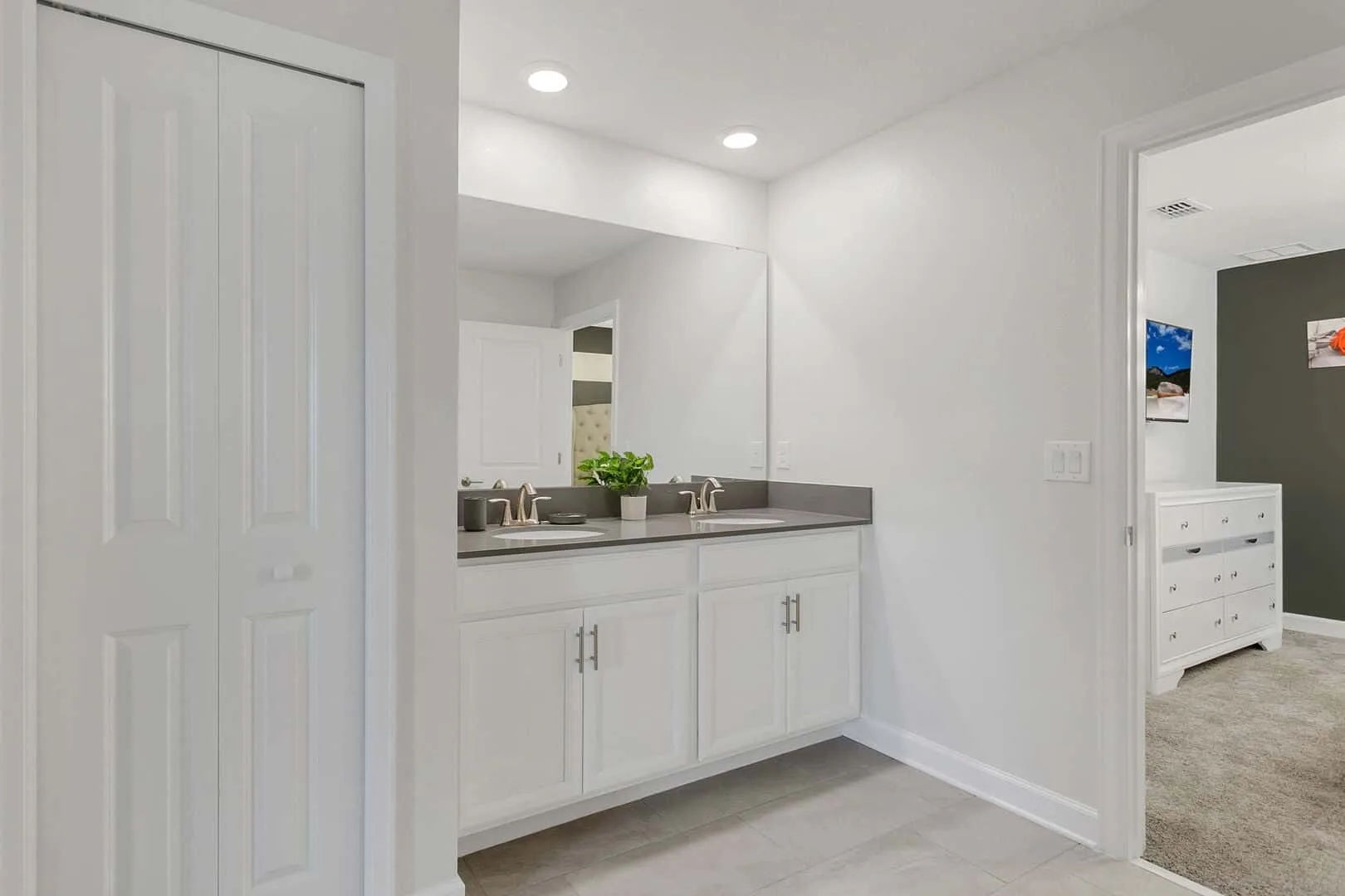 Un tocador de baño luminoso con lavabo y armarios blancos.