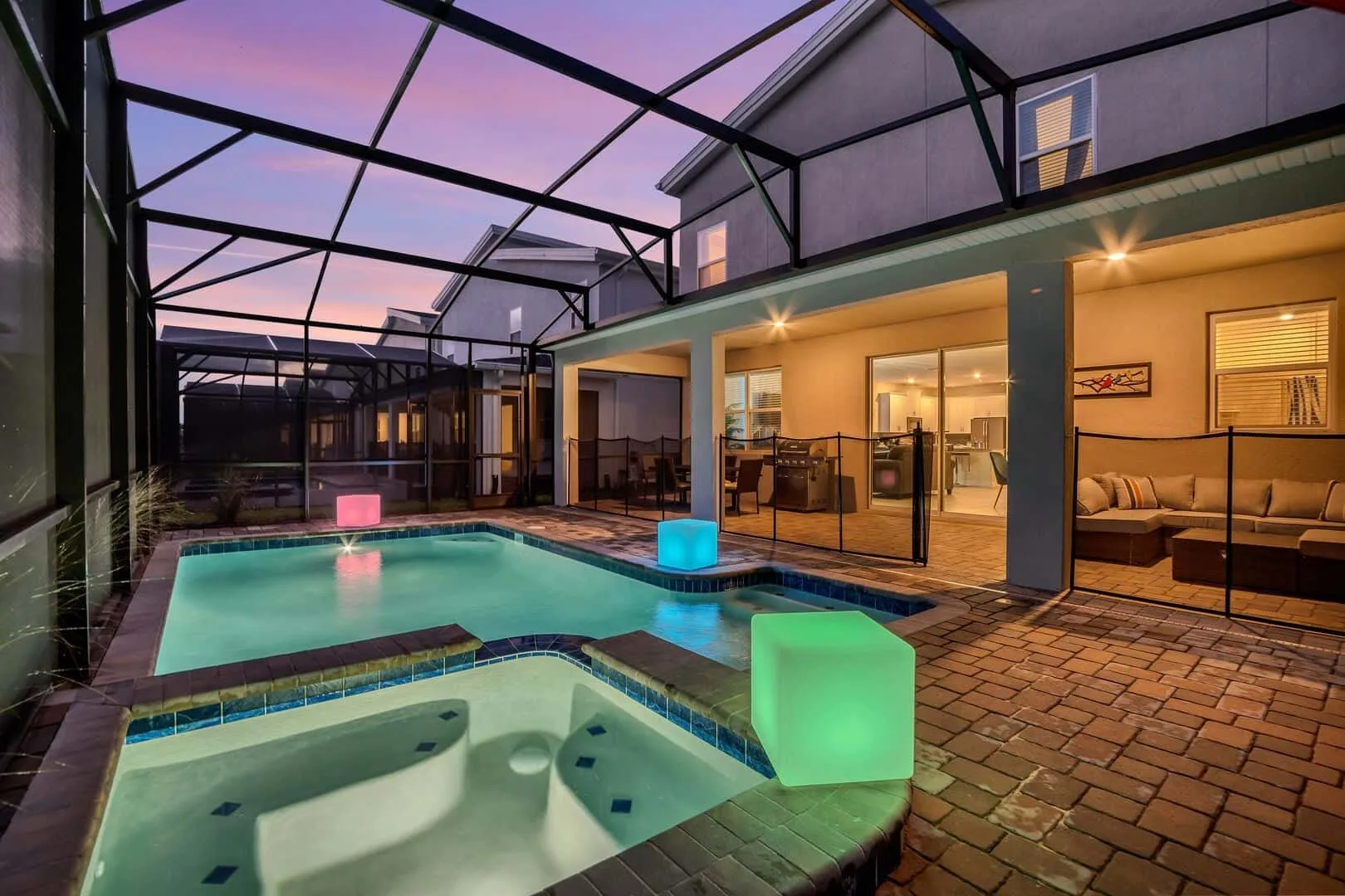 Zona de piscina interior con spa y cubos de luz junto a puertas de vidrio.