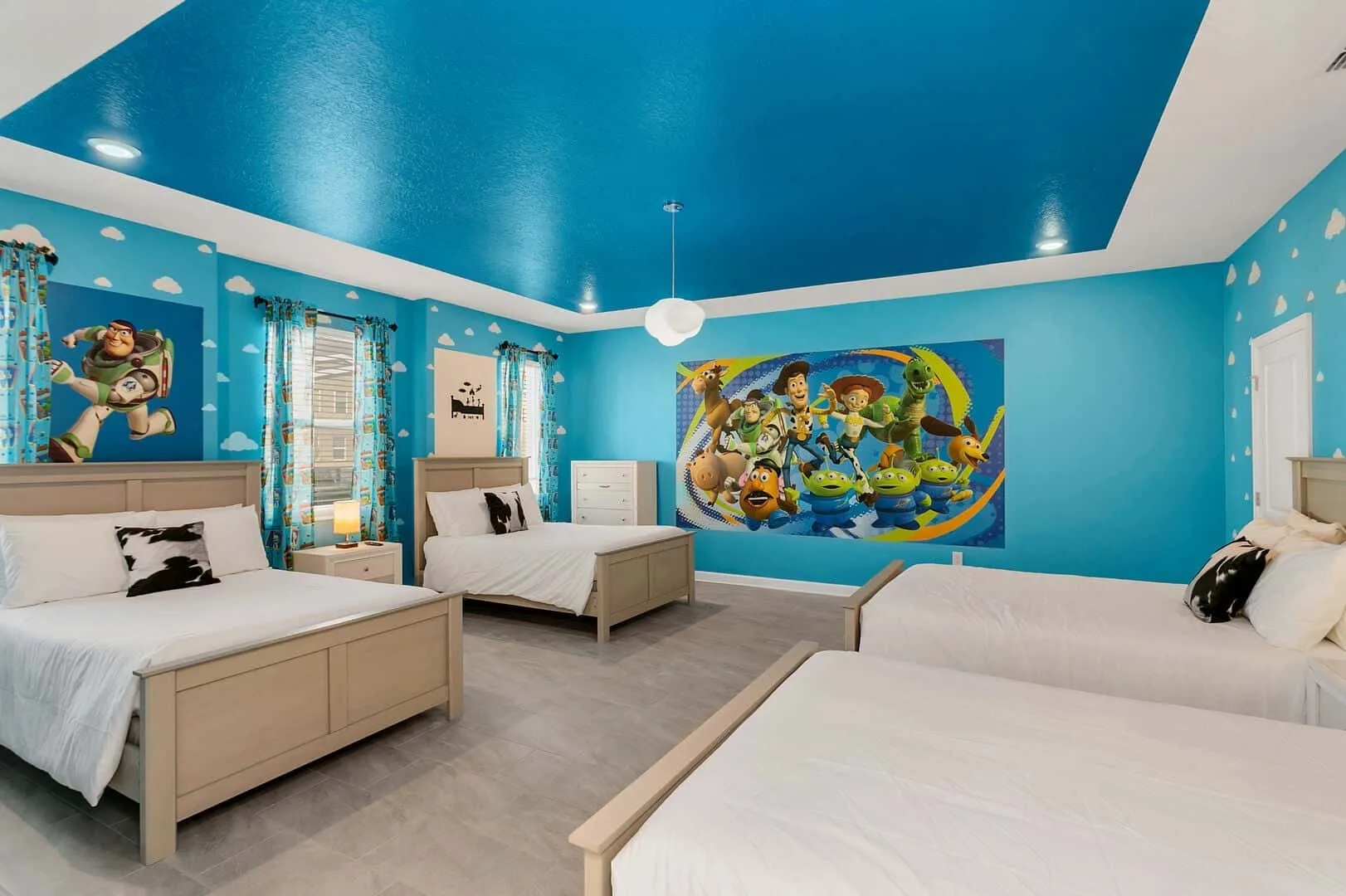 Un dormitorio azul vibrante con camas, arte de dibujos animados y un ventilador de techo.