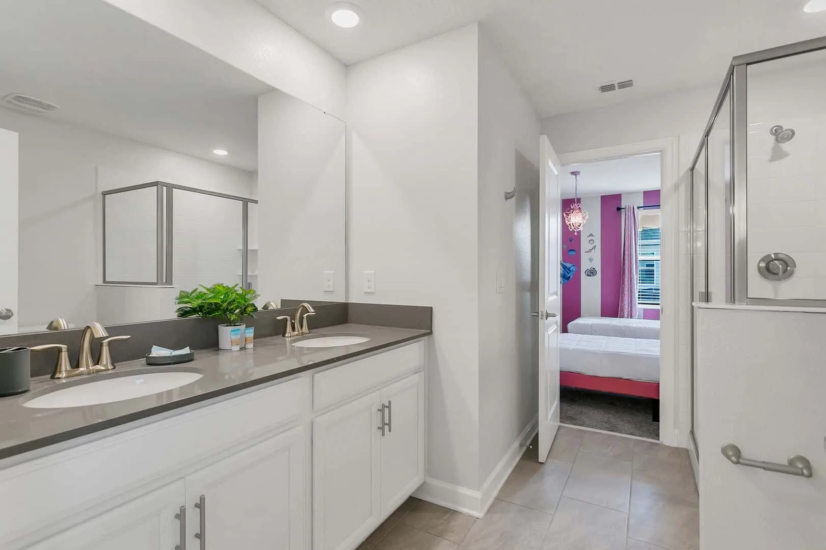 Un tocador de baño y una ducha dan a un dormitorio con decoraciones coloridas en la pared.