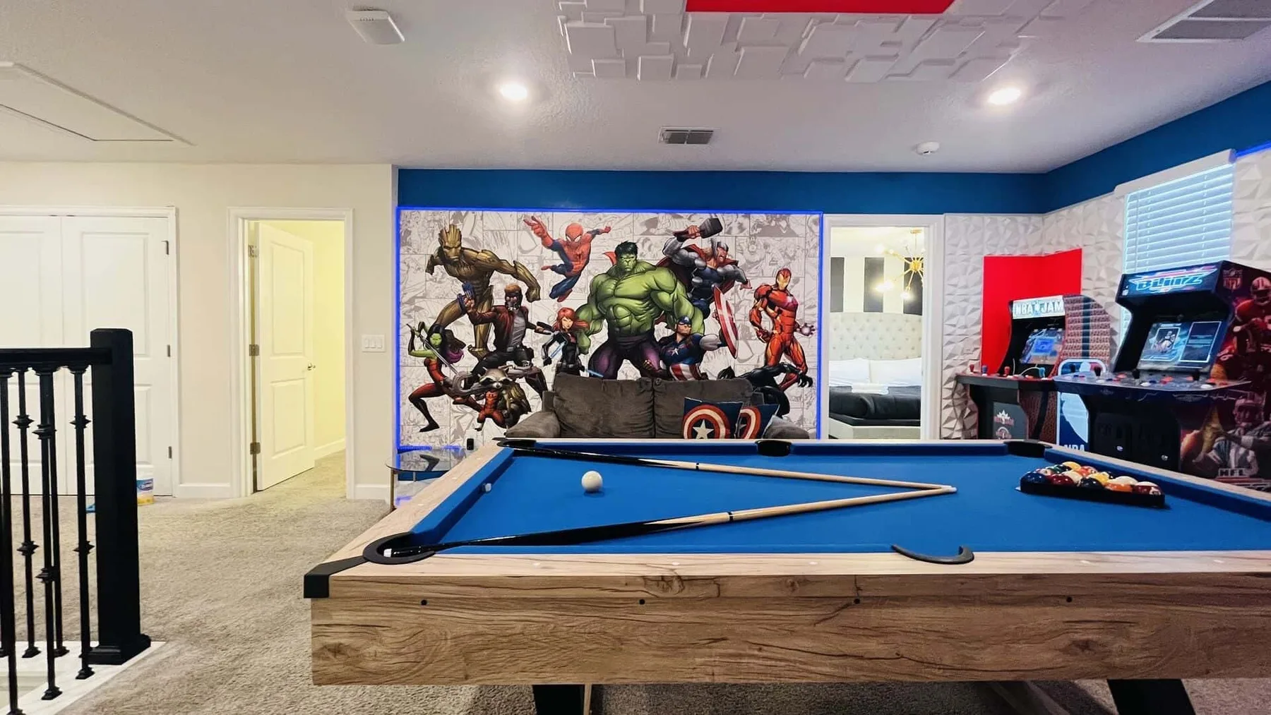 Una sala de juegos cuenta con una mesa de billar y un mural colorido de superhéroes.