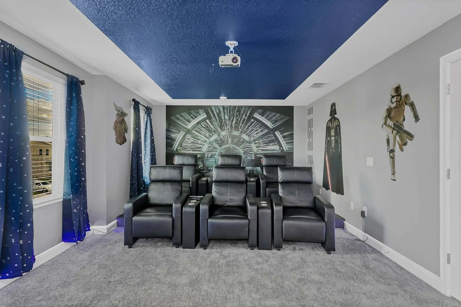 Un cine en casa con asientos reclinables frente a una pantalla grande.
