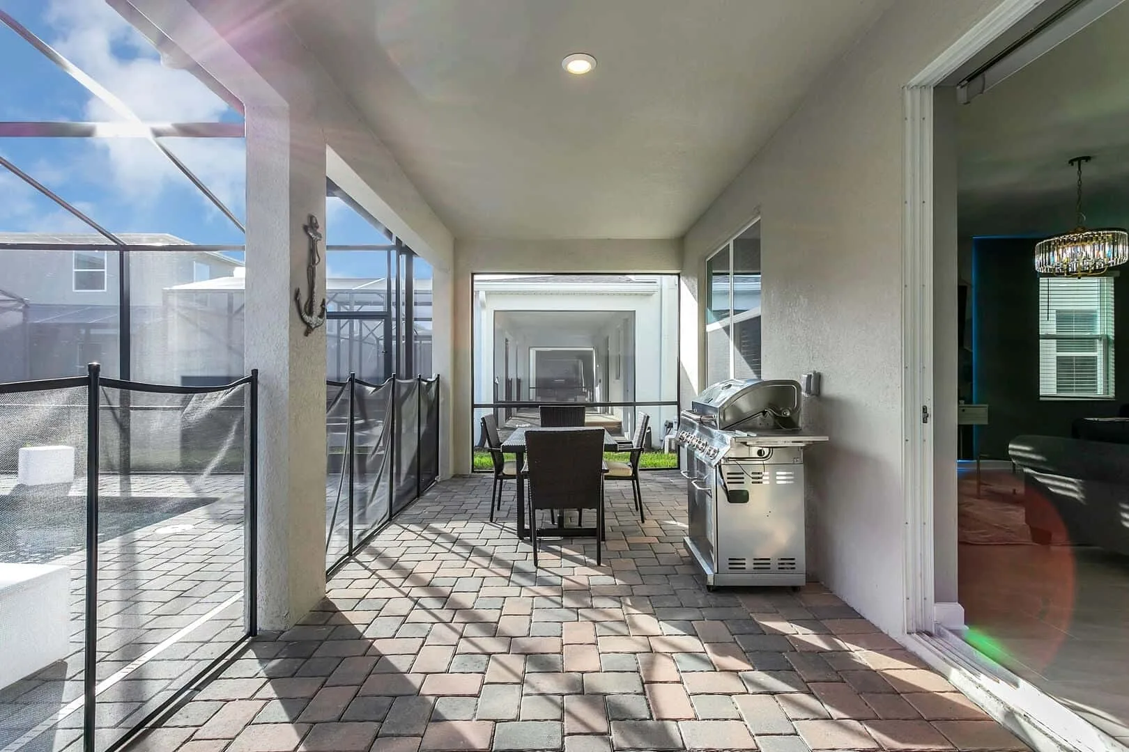 Un patio cubierto con mesa de comedor y parrilla junto a la piscina.