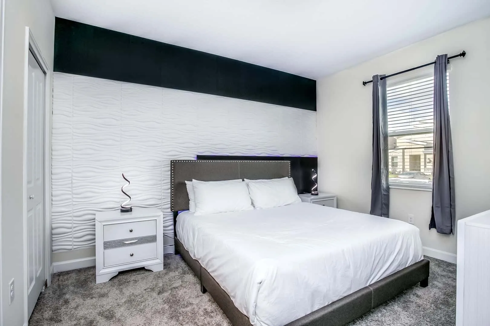 Un dormitorio con una cama junto a una pared texturizada y una ventana.