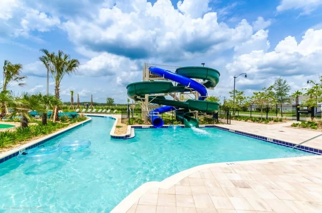 Una piscina al aire libre con un tobogán azul y palmeras.