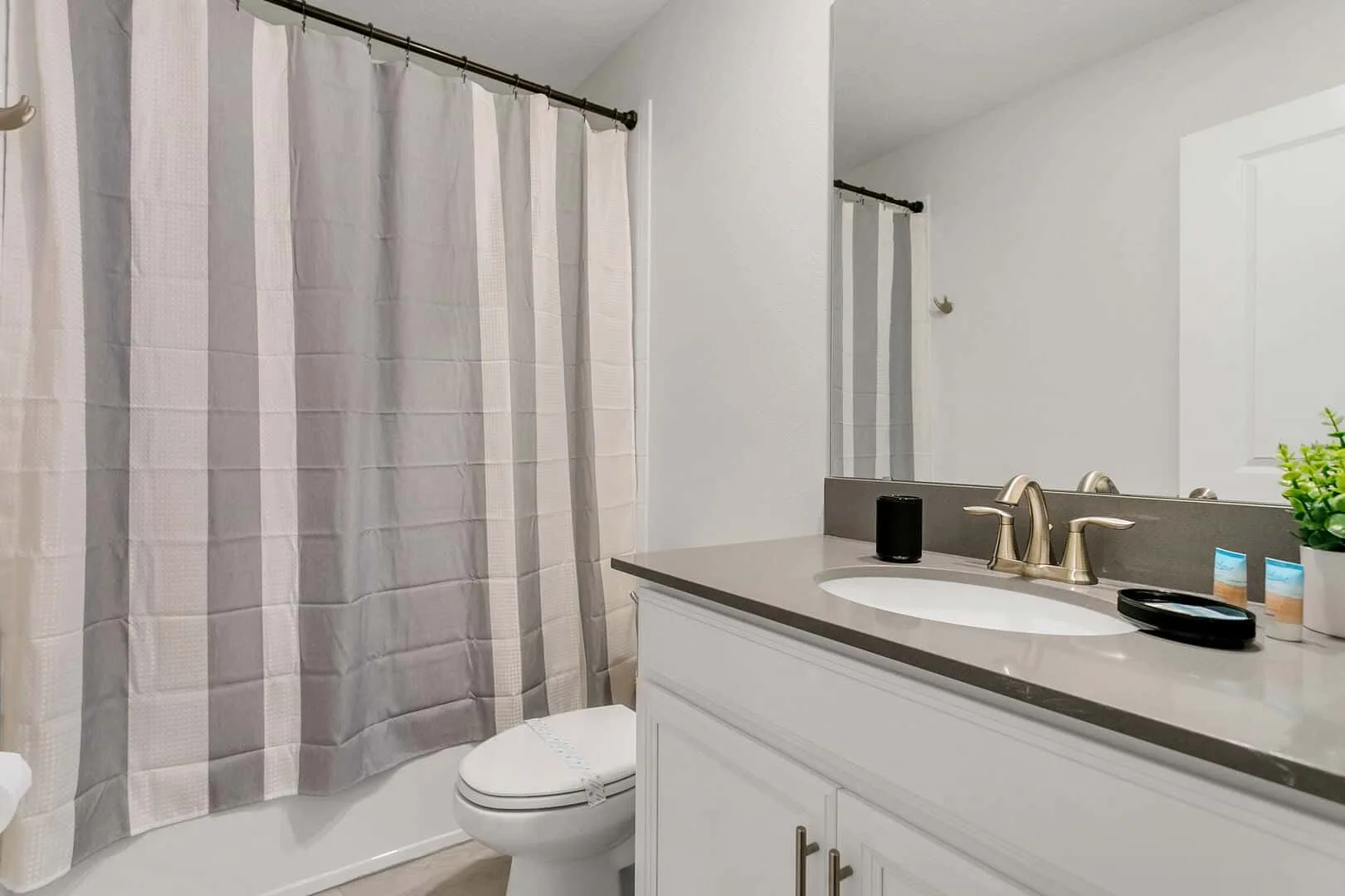 Un baño con bañera, cortina de ducha, inodoro y lavabo.