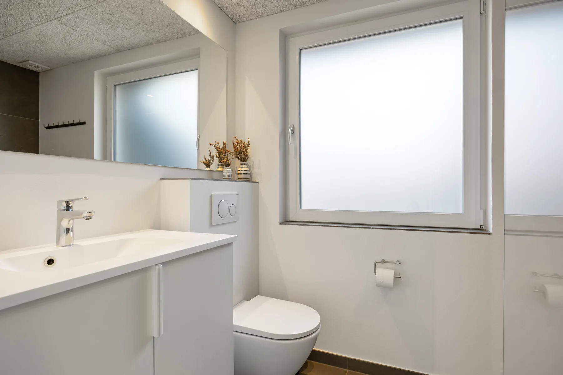 Un baño luminoso con lavabo, inodoro y ventana esmerilada.