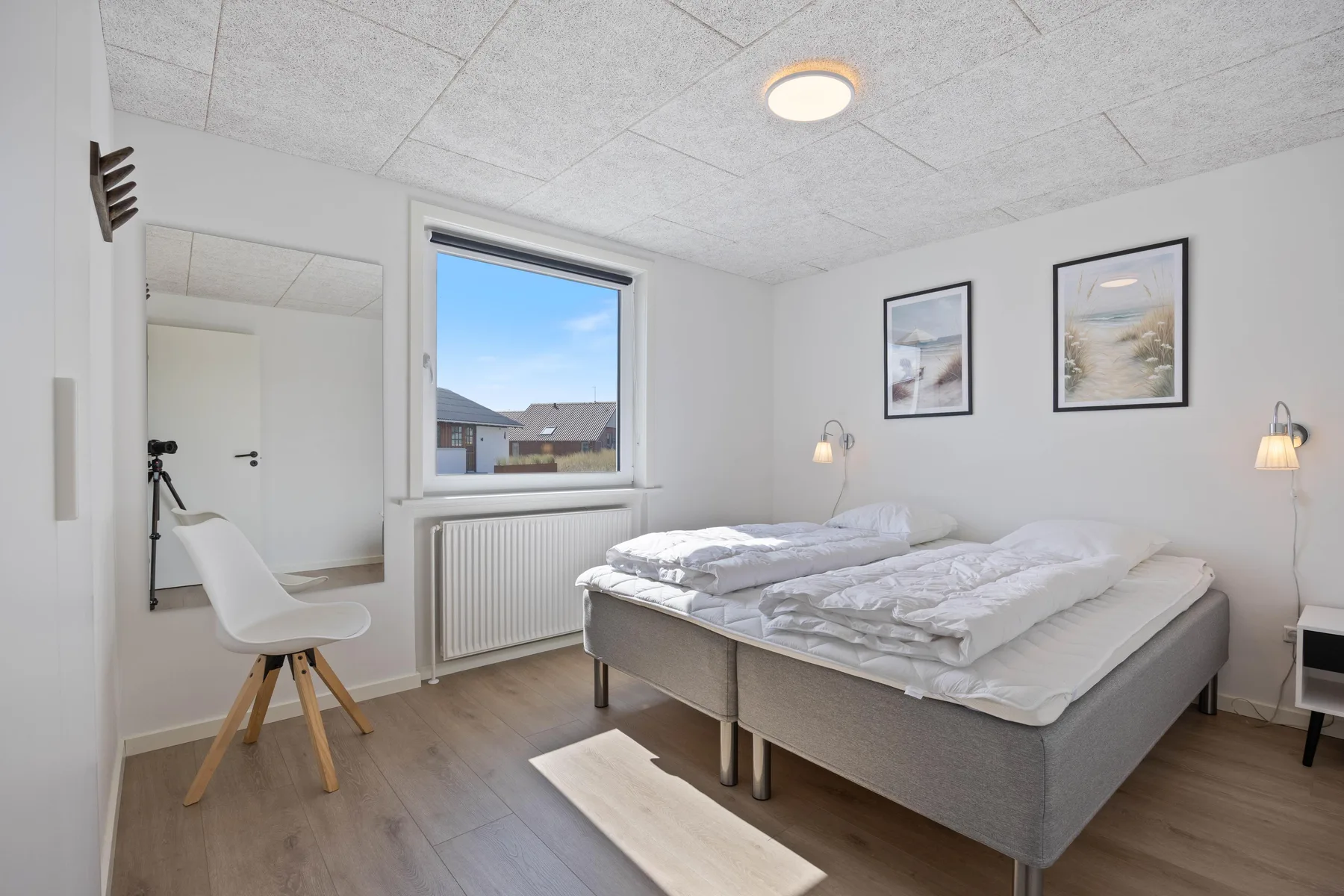 Un dormitorio con dos camas, una ventana y cuadros enmarcados en la pared.