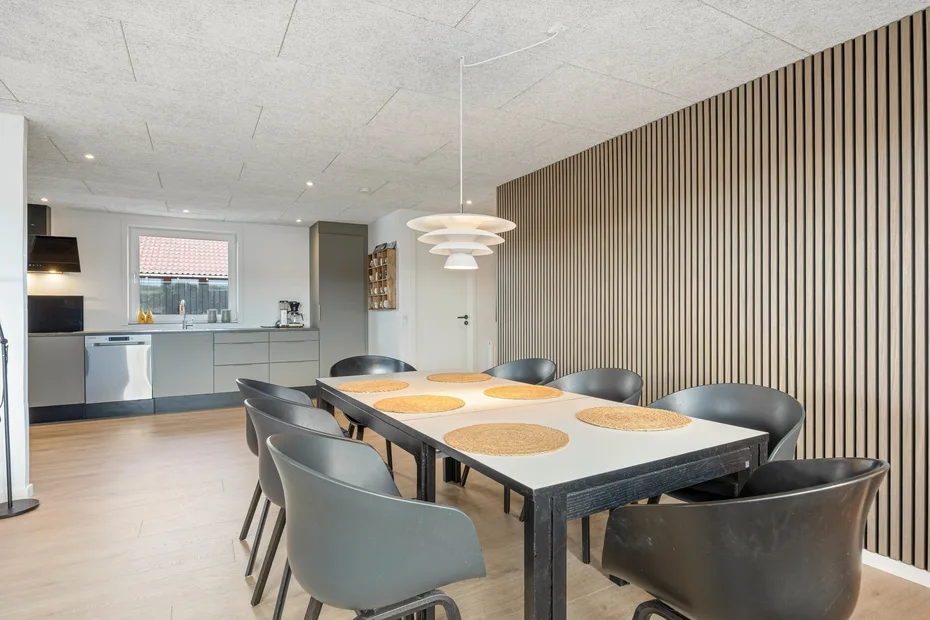 Comedor con una mesa larga y asientos junto a una cocina abierta.