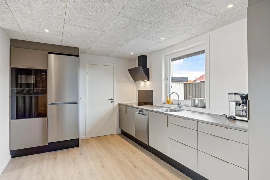 Una cocina moderna con gabinetes grises, una placa de cocina y una ventana sobre el fregadero.