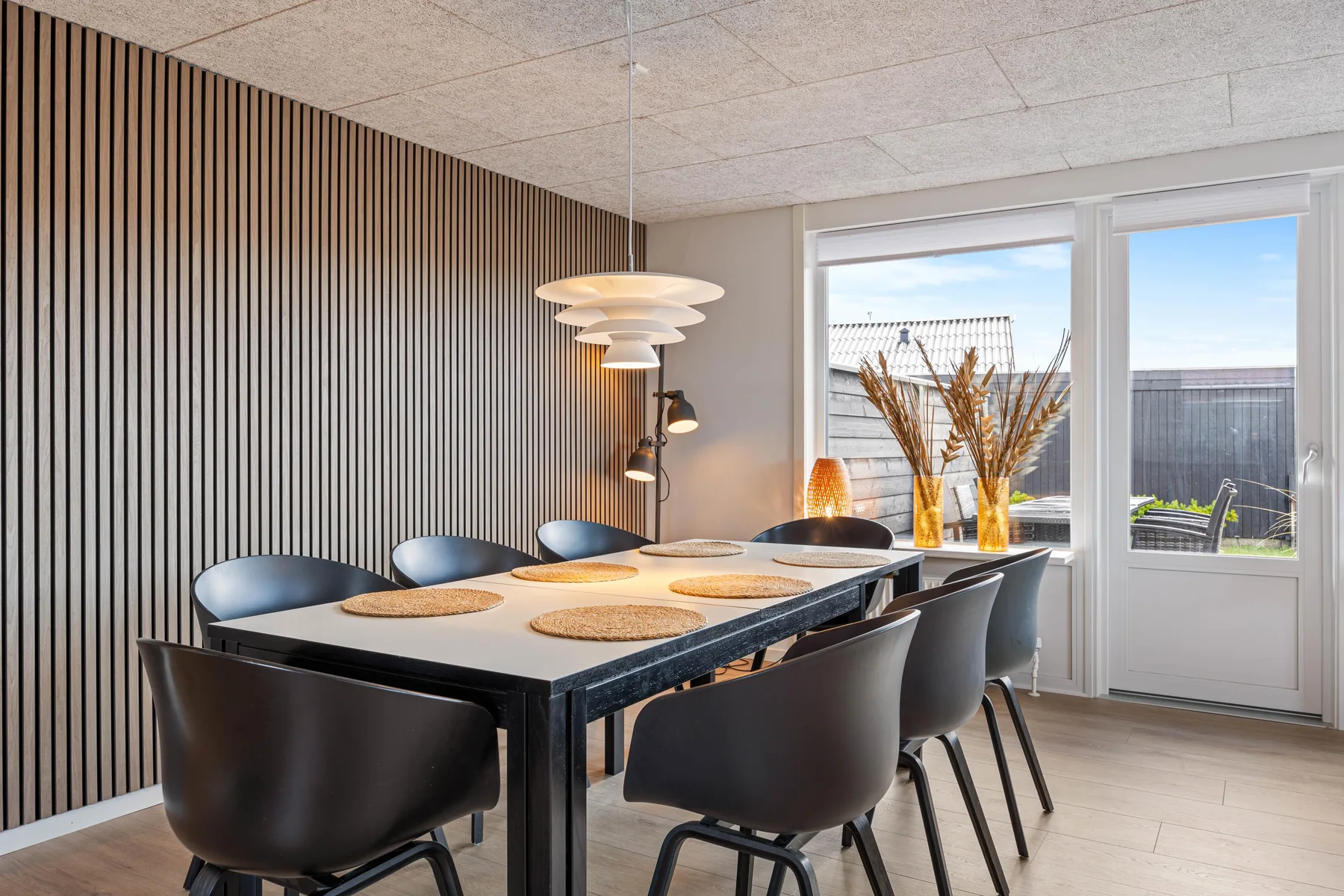 Comedor con una mesa larga y asientos junto a grandes ventanas.