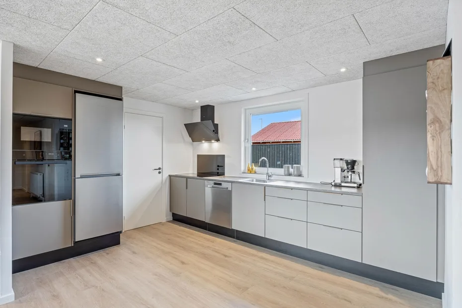 Una cocina moderna con gabinetes grises, una placa de cocción y una ventana sobre el fregadero.