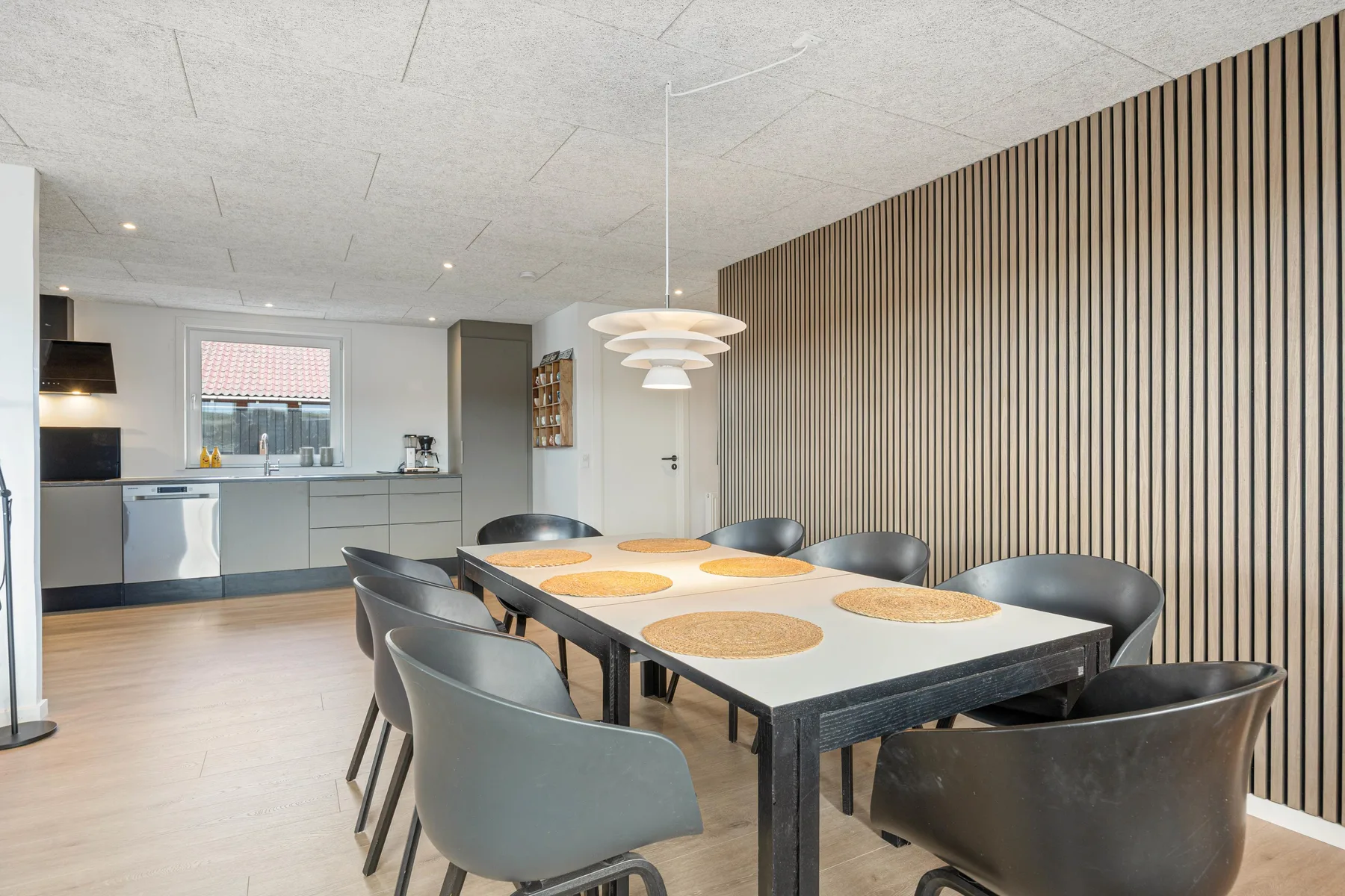 Comedor con una mesa larga y sillas junto a una cocina abierta.
