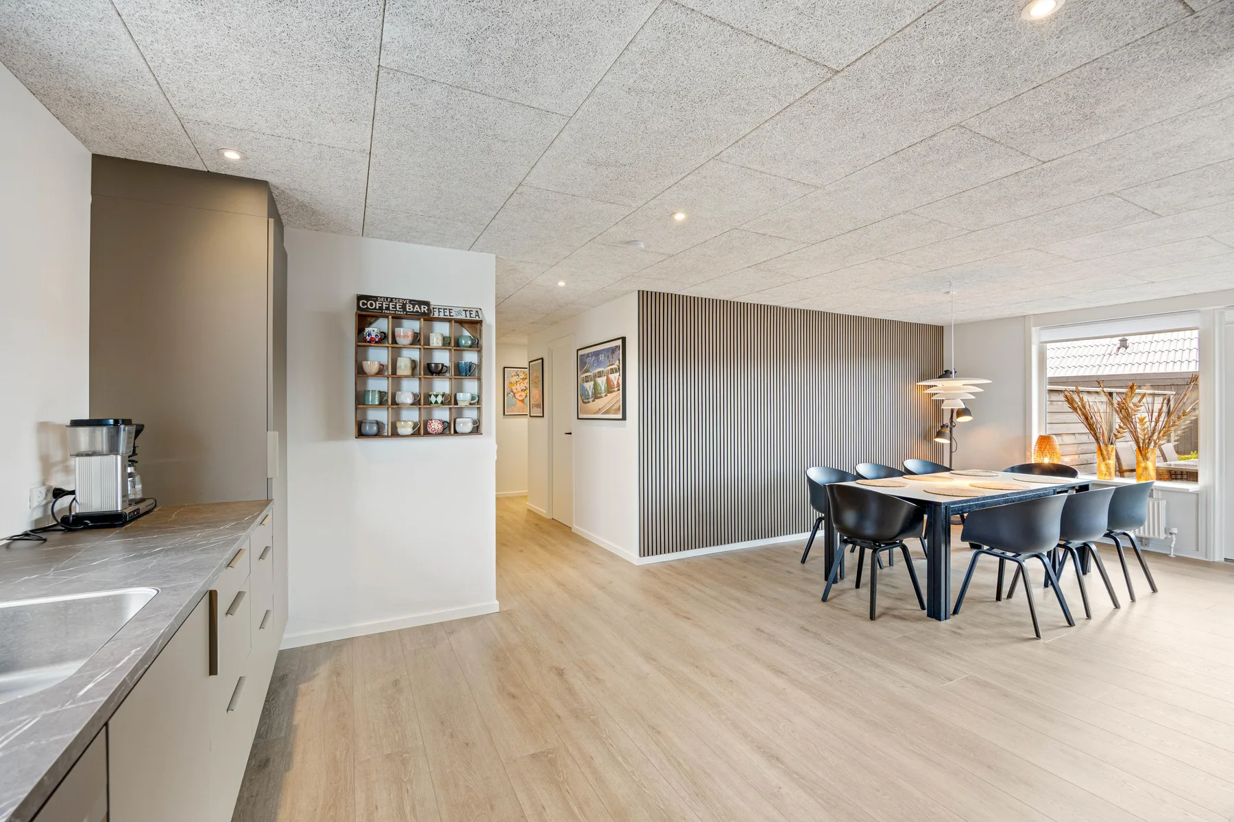 Una cocina y comedor de planta abierta con una mesa junto a las ventanas.