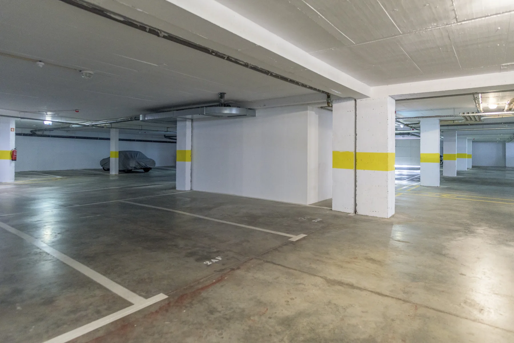 An underground parking garage with painted lines and concrete support columns.