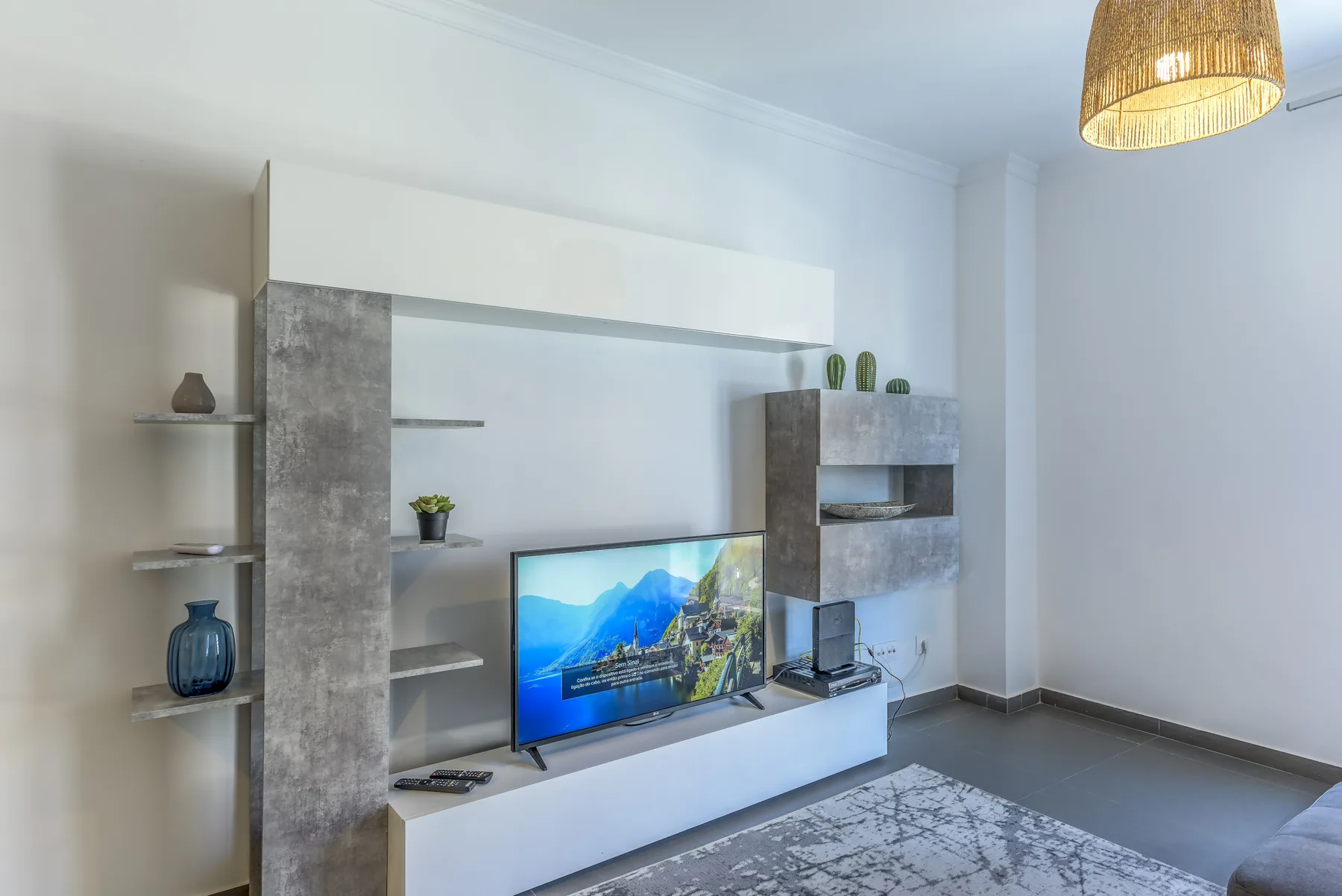 Sala de estar con un televisor en un mueble empotrado y una alfombra.
