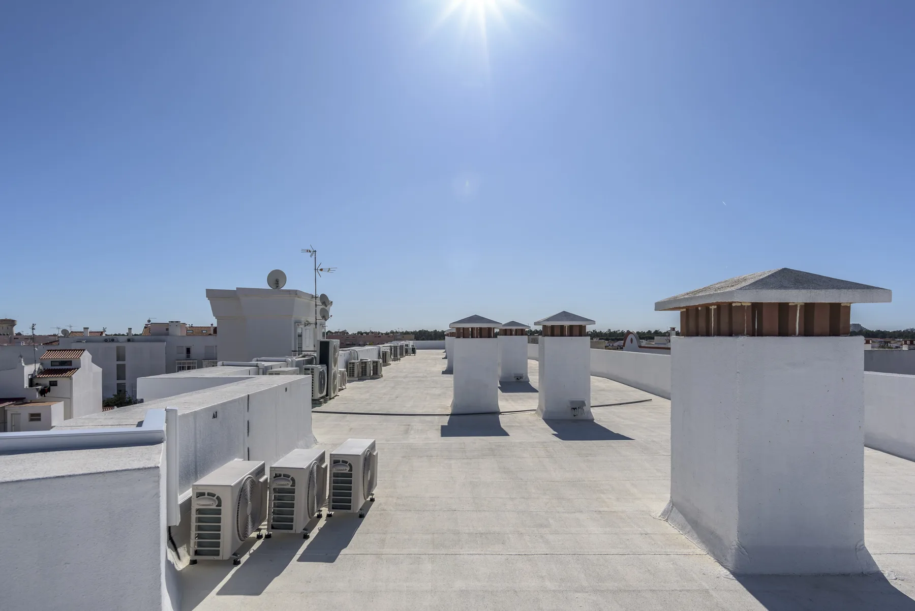 Una azotea plana con estructuras de ventilación blancas bajo un cielo despejado.