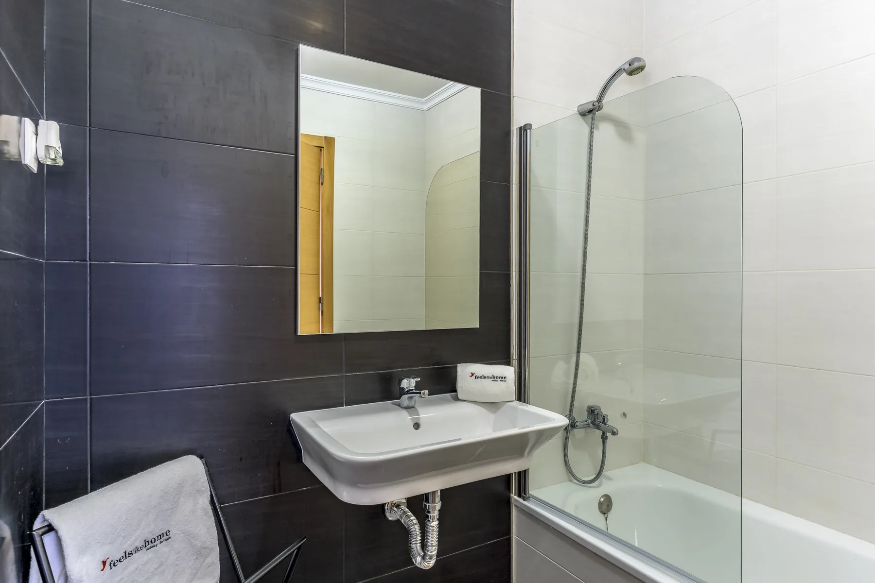 Un baño con lavabo, espejo y bañera con ducha.