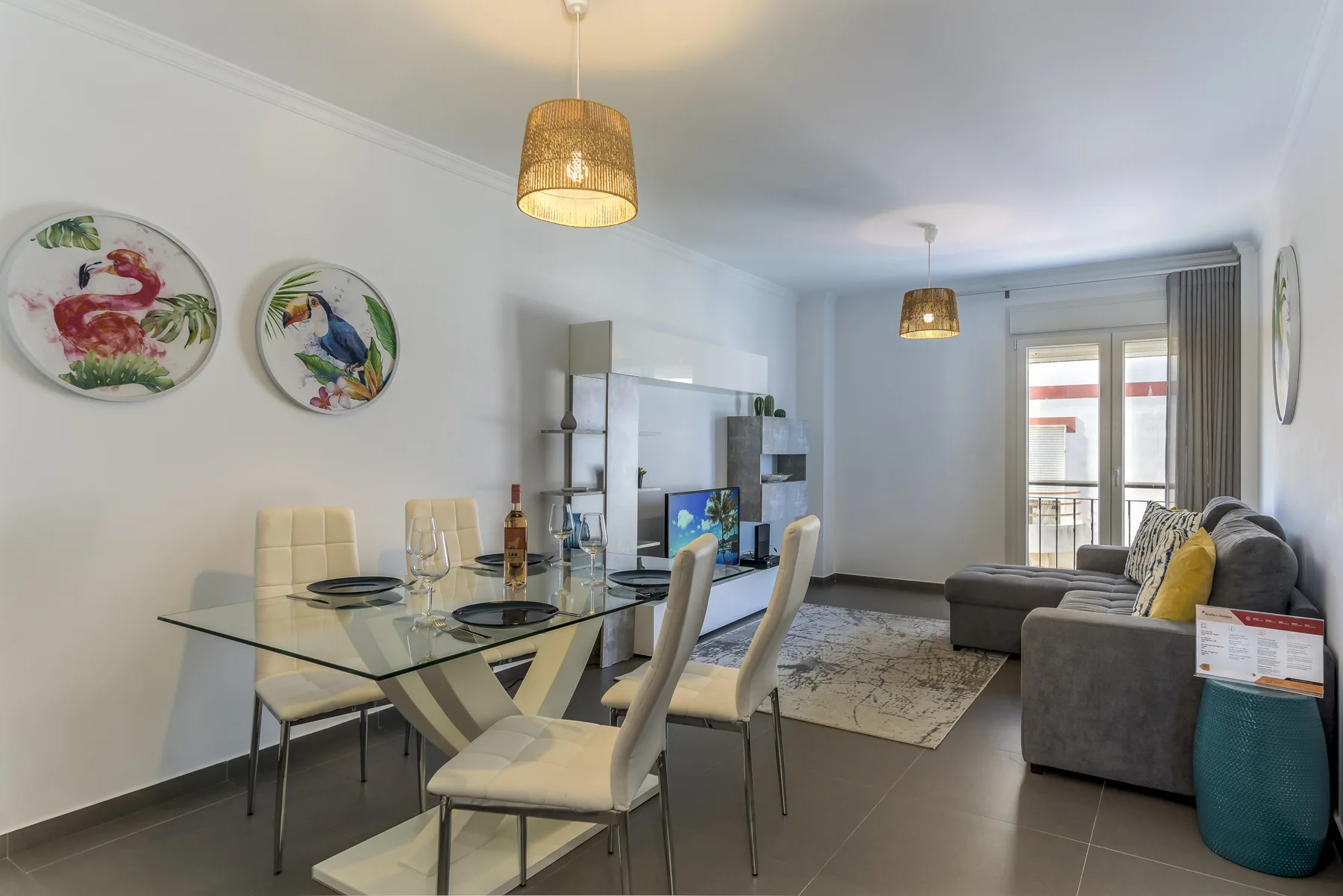 A living and dining area with a glass dining table and seating beside the sofa.