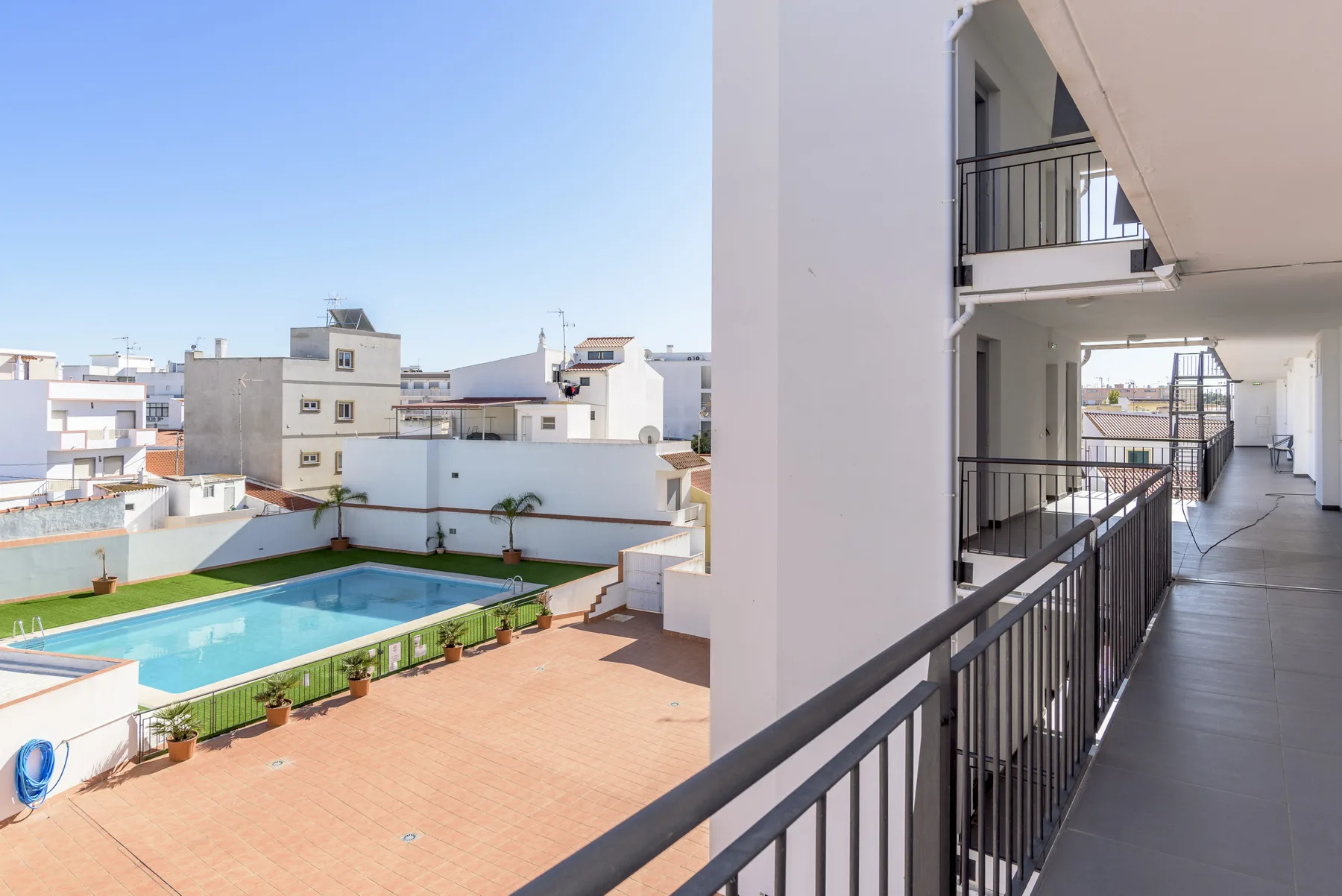 Un balcón da a una piscina y a edificios vecinos.