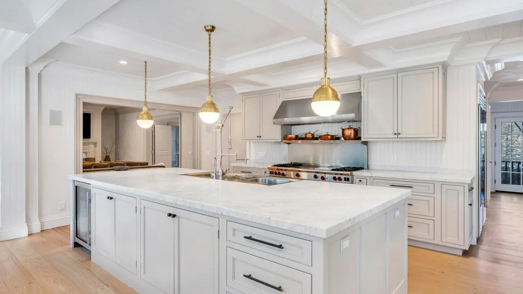 Una cocina luminosa con una gran isla central y lámparas colgantes.