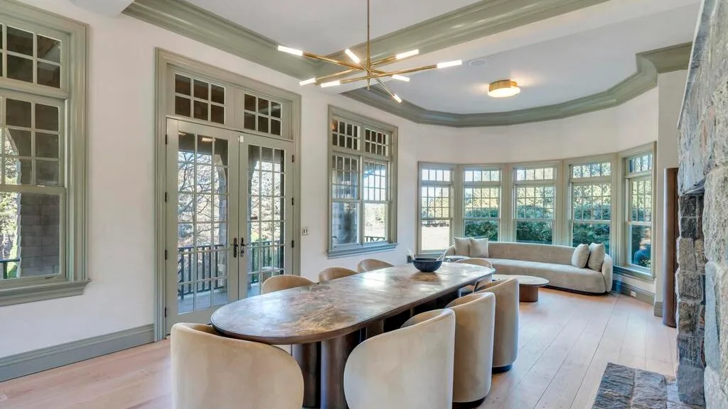Un luminoso comedor y sala de estar cuenta con una mesa larga y asientos curvos junto a las ventanas.
