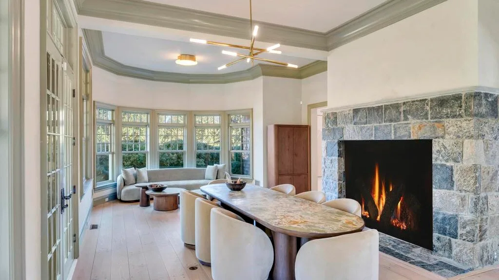 Una sala luminosa con una mesa larga, asientos tapizados y una chimenea de piedra.