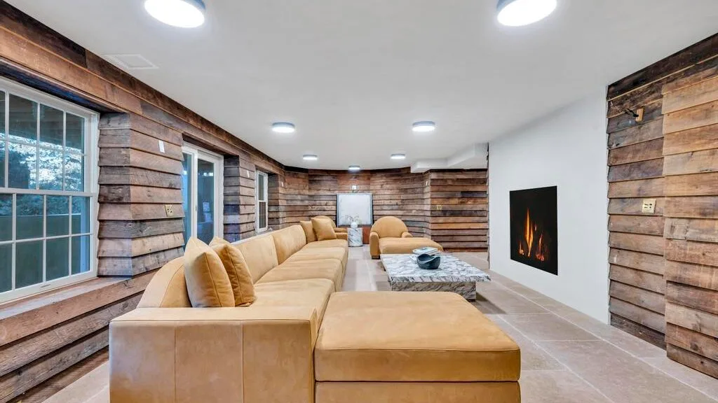 Una sala de estar con asientos beige y una chimenea empotrada en la pared.