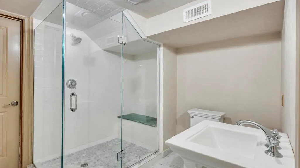 Un baño con una ducha de vidrio y un lavabo blanco.