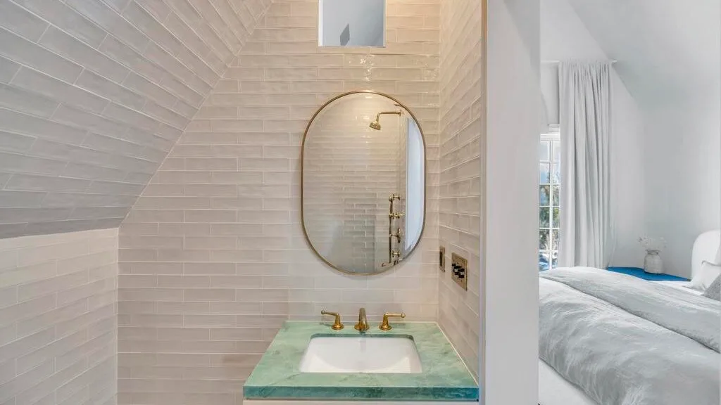 Un lavabo de baño revestido de azulejos con un espejo redondo.
