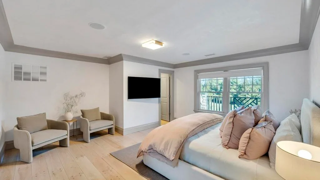 Un dormitorio luminoso con una cama grande y una zona de estar junto a la ventana.