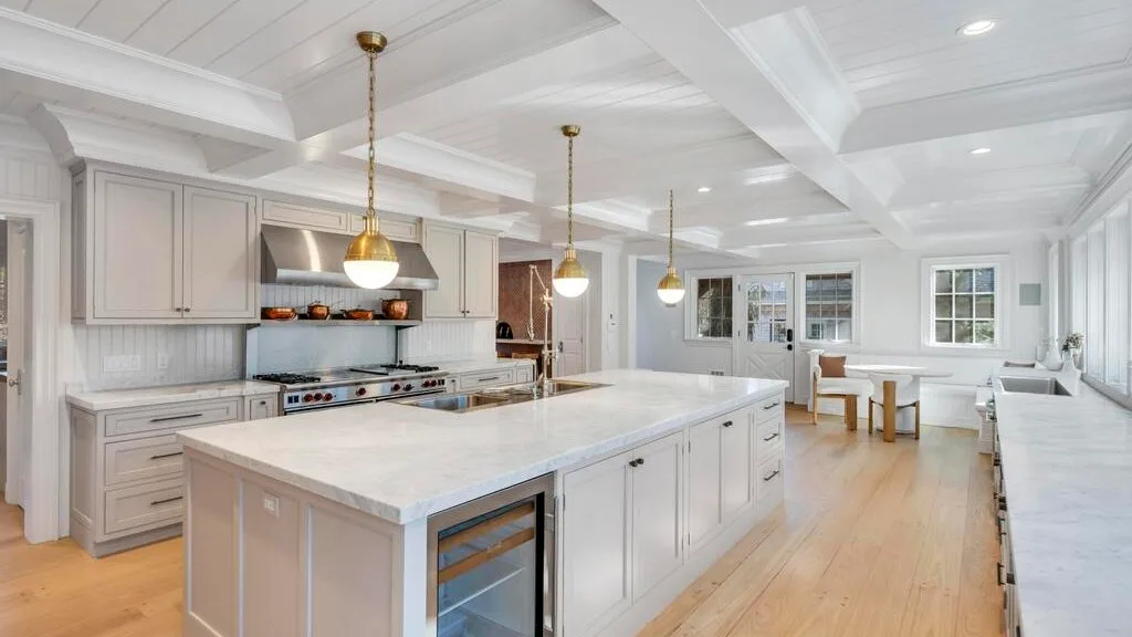 Una cocina luminosa con una isla grande se abre a un comedor.