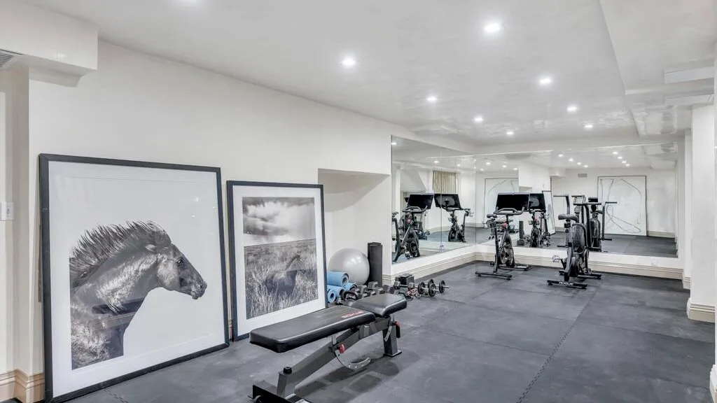 Un gimnasio con equipos de ejercicio y cuadros de caballos apoyados contra la pared.