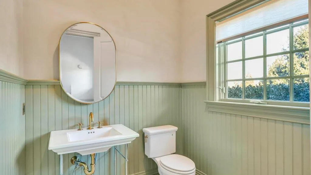 Un baño con lavabo, inodoro y una ventana amplia.