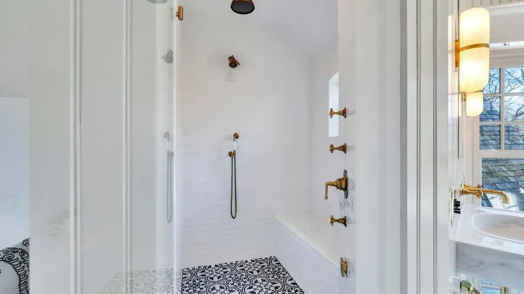 Un baño luminoso con una ducha de azulejos y un lavabo junto a una ventana.