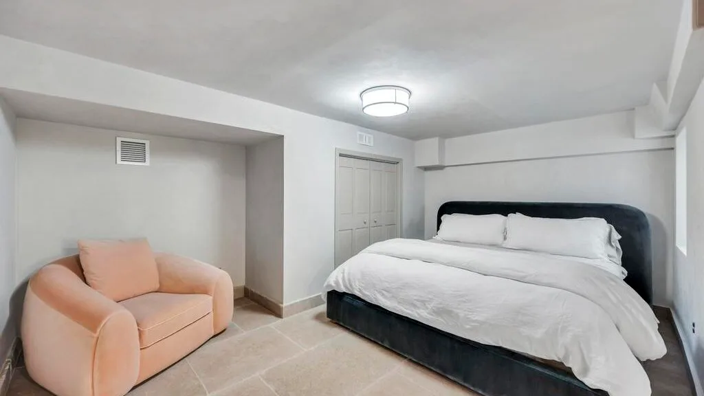 Un dormitorio con una cama grande y un sillón color melocotón.