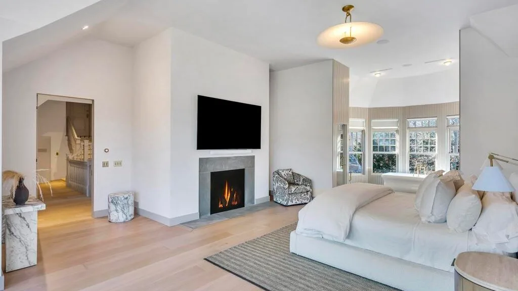 Una sala luminosa con un sofá blanco, una chimenea y un televisor.