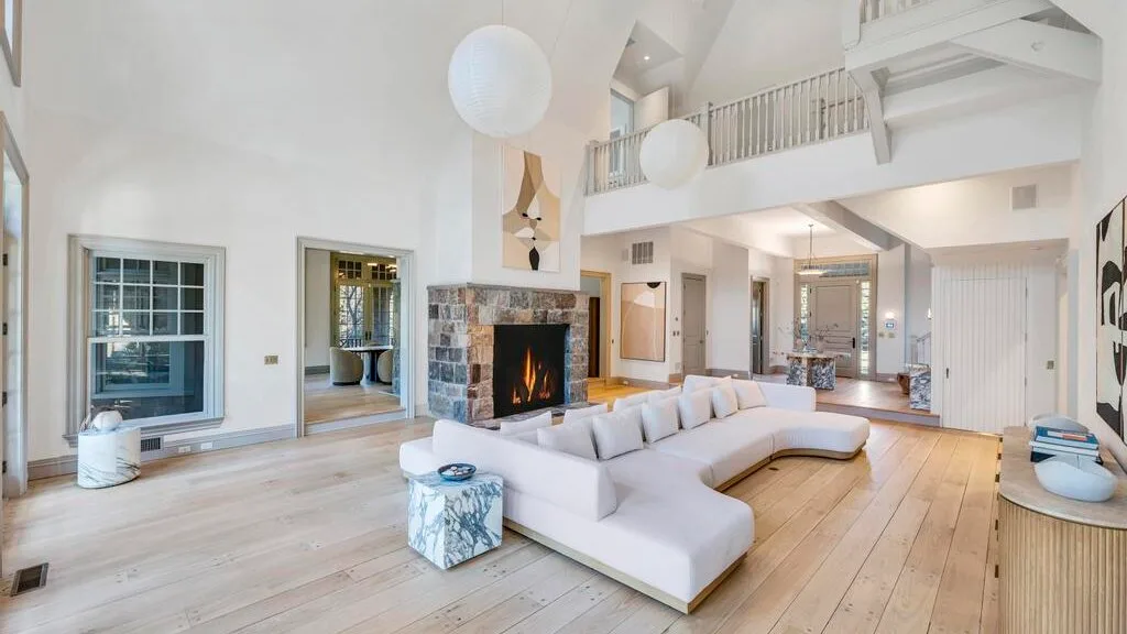 Una sala luminosa con una amplia zona de asientos y una chimenea de piedra.