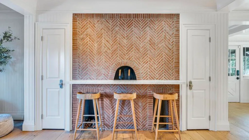 Una barra con asientos de madera está frente a una pared de ladrillo decorativo.